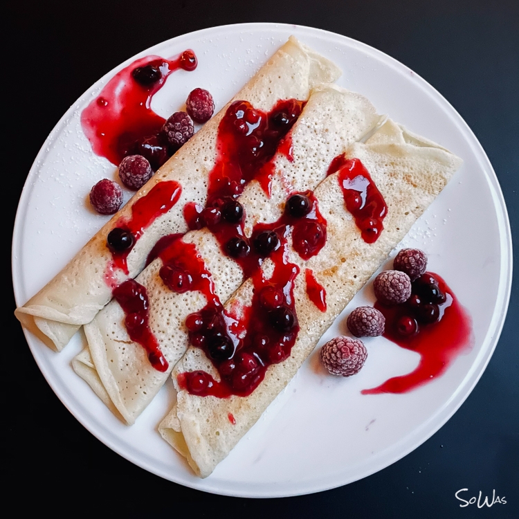 Drei Crepes auf einem Teller mit Beeren Sauce