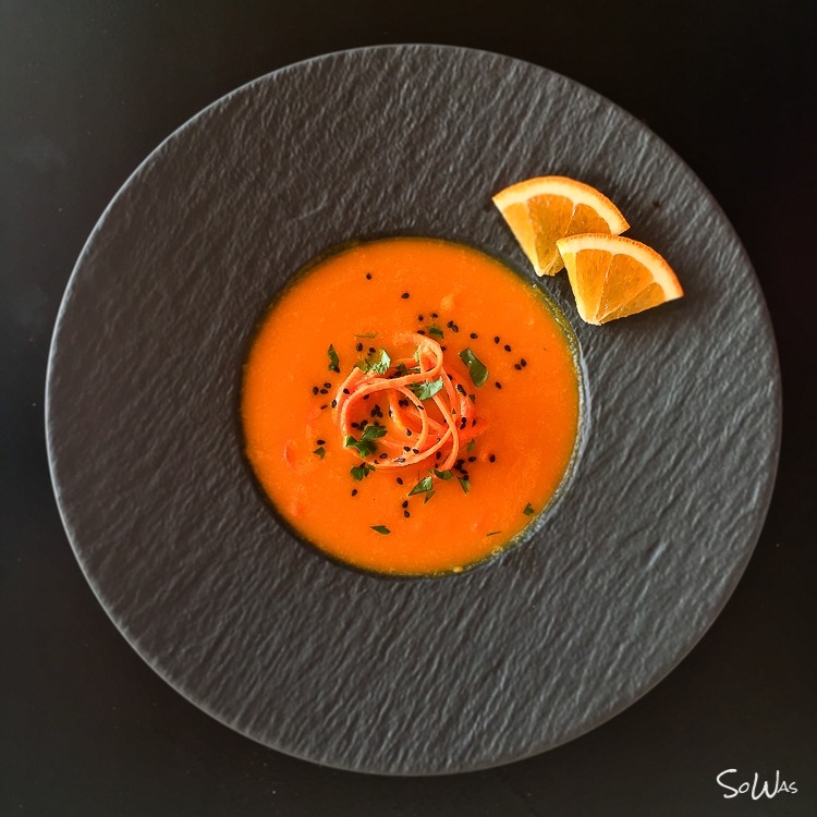 Ein Teller mit Korottensuppe und zwei Orangen Stücken